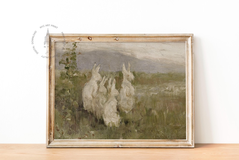 May include: A vintage painting of a group of white rabbits in a field. The rabbits are gathered together in a grassy area with a mountain range in the background. The painting is framed in a light wood frame.