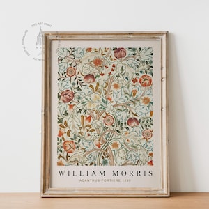 Op de afbeelding: Een ingelijste print van een vintage bloemenontwerp van William Morris. De print heeft een herhalend patroon van gestileerde bloemen en bladeren in tinten rood, oranje, geel, groen en blauw. De tekst "William Morris Acanthus Portiere 1880" is onder het ontwerp gedrukt.