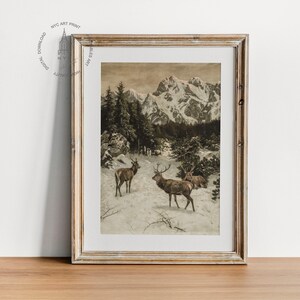 May include: A framed vintage print depicting a snowy mountain landscape with three deer in the foreground. The print is in shades of brown and white, with a subtle sepia tone.