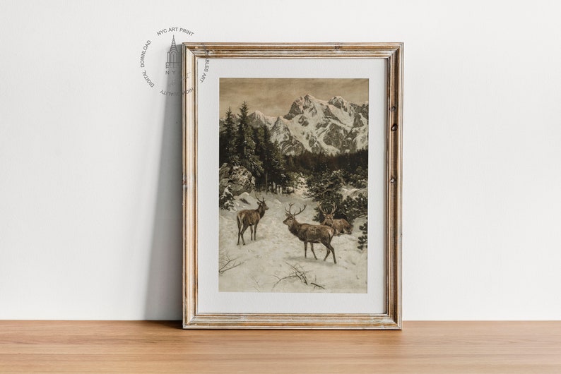 May include: A framed vintage print depicting a snowy mountain landscape with three deer in the foreground. The print is in shades of brown and white, with a subtle sepia tone.