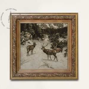 May include: A framed print depicting a winter scene with three deer in a snowy forest. The deer are brown with large antlers. The forest is dark green and the snow is white. The frame is gold and ornate.
