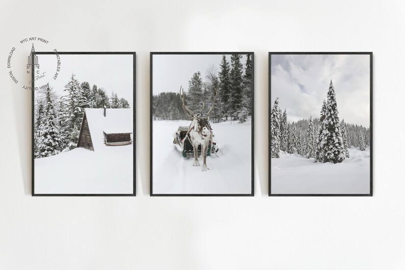 May include: Set of three framed winter landscape prints. The prints feature snowy scenes: a cabin, a reindeer pulling a sled, and a forest of snow-covered trees. The prints are in black frames.