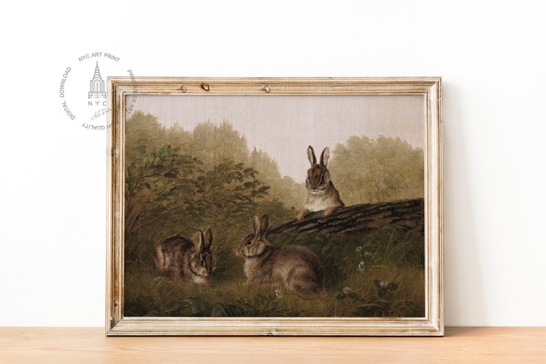 May include: A vintage painting of three brown rabbits in a forest setting. The rabbits are sitting on a log and in the undergrowth. The painting is framed in a light wood frame.