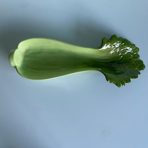 Może przedstawiać: Zielona ceramiczna salaterka w kształcie selera z liściastym wierzchołkiem. Salaterka została zaprojektowana tak, aby przypominała łodygę selera.