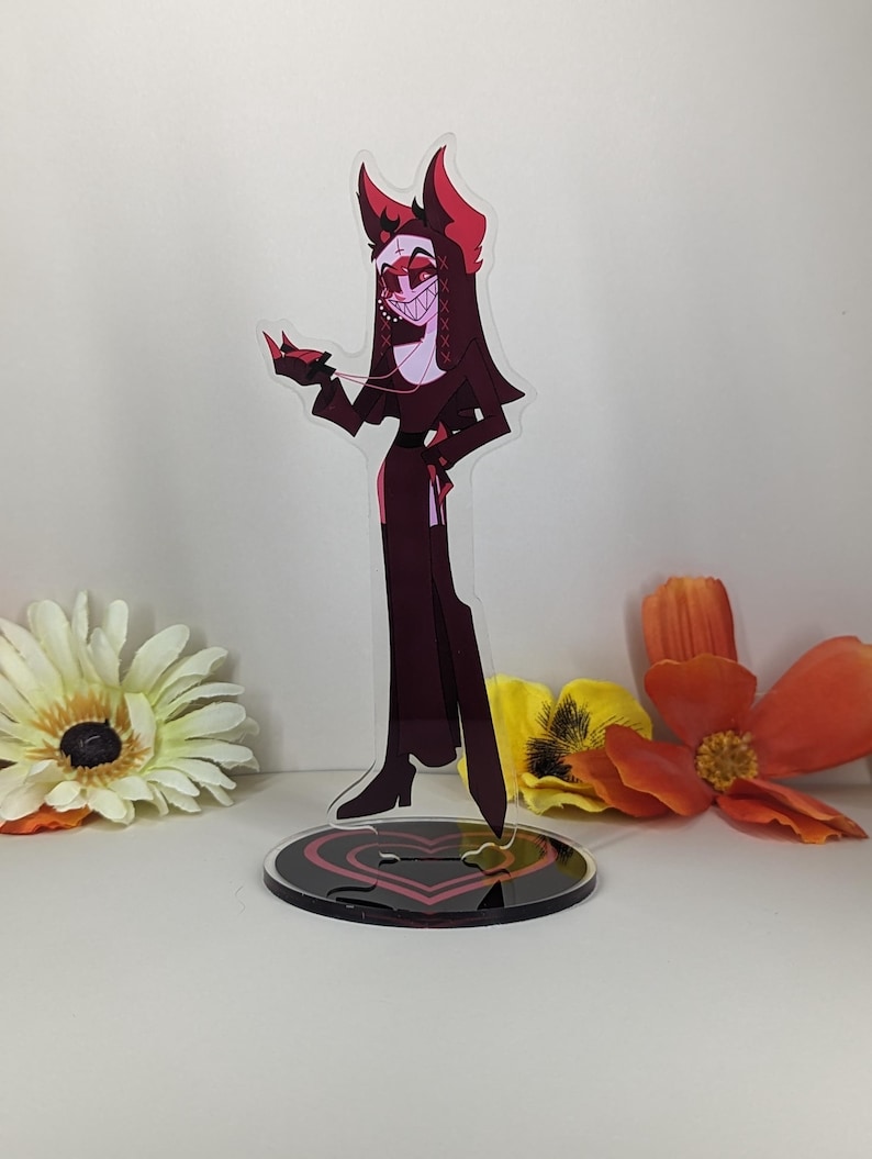 Puede incluir: Una figura de pie de acr&iacute;lico de un personaje de dibujos animados con cuernos, que lleva un vestido negro y est&aacute; de pie sobre una base con un coraz&oacute;n rojo.