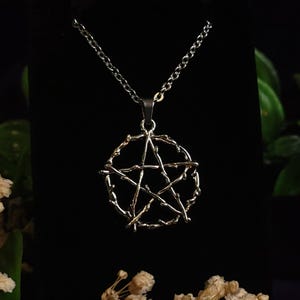 May include: A silver necklace with a pentagram pendant made of twisted wire. The pendant is a circle with a five-pointed star inside.