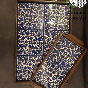 Puede incluir: Dos bandejas de servir de madera con inserciones de azulejos florales azules y blancos. La bandeja m&aacute;s grande tiene cuatro azulejos y la bandeja m&aacute;s peque&ntilde;a tiene dos azulejos.