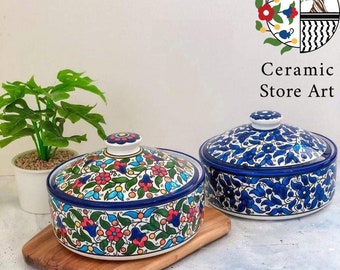 May include: Two ceramic bowls with lids, featuring a colorful floral pattern in shades of blue, green, red, and yellow. The bowls are on a wooden surface. The text "Ceramic Store Art" is visible in the image.