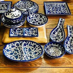 Może przedstawiać: Zestaw niebieskich i białych ceramicznych naczyń z kwiatowymi wzorami. Naczynia obejmują talerz do serwowania, małą miskę, podstawkę pod łyżkę i mały talerzyk.