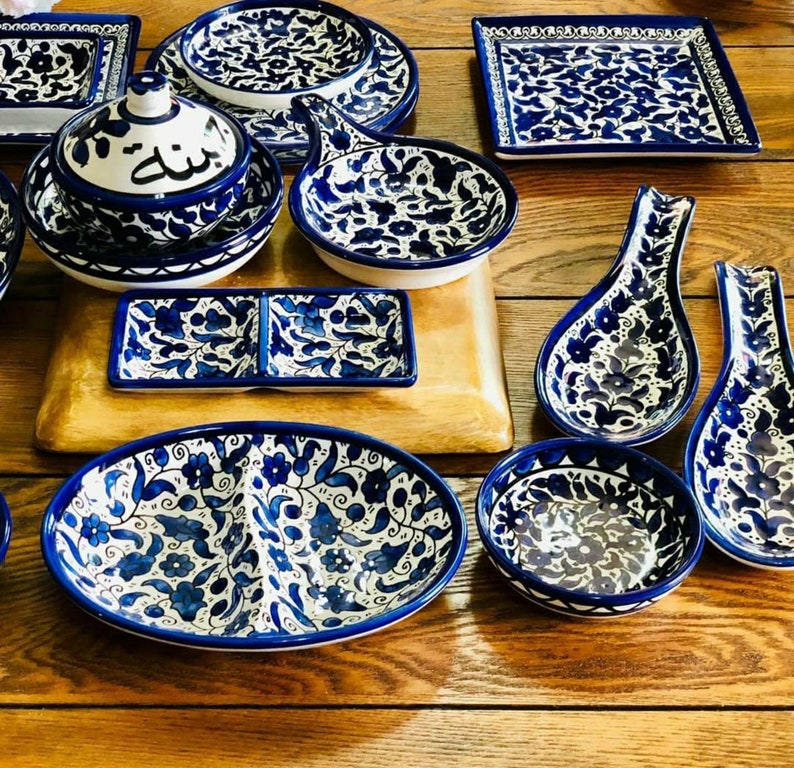 Może przedstawiać: Zestaw niebieskich i białych ceramicznych naczyń z kwiatowymi wzorami. Naczynia obejmują talerz do serwowania, małą miskę, podstawkę pod łyżkę i mały talerzyk.