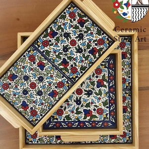 Puede incluir: Tres bandejas de servir de madera con intrincados dise&ntilde;os florales en azul, rojo, verde y amarillo. Las bandejas est&aacute;n anidadas, con la bandeja m&aacute;s grande en la parte inferior y la bandeja m&aacute;s peque&ntilde;a en la parte superior.