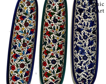 May include: Three ceramic serving dishes with a floral pattern in shades of blue, green, red, and yellow. The dishes are oval shaped and have a white background.