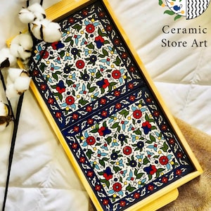 Puede incluir: Una bandeja de servir de madera con dos azulejos de cer&aacute;mica extra&iacute;bles. Los azulejos presentan un patr&oacute;n floral colorido en tonos de azul, rojo, verde y blanco. La bandeja tiene un acabado de madera natural y dos asas.