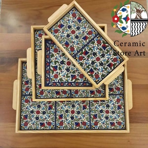 Puede incluir: Conjunto de cuatro bandejas de madera con azulejos de cer&aacute;mica con motivos florales. Los azulejos presentan un dise&ntilde;o floral azul, blanco, verde y rojo. Las bandejas est&aacute;n apiladas unas sobre otras.