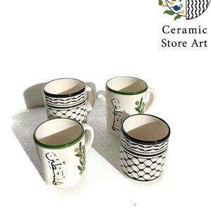 May include: Set of four white ceramic mugs with black and green designs. The mugs feature a geometric pattern, olive branches, and Arabic calligraphy.