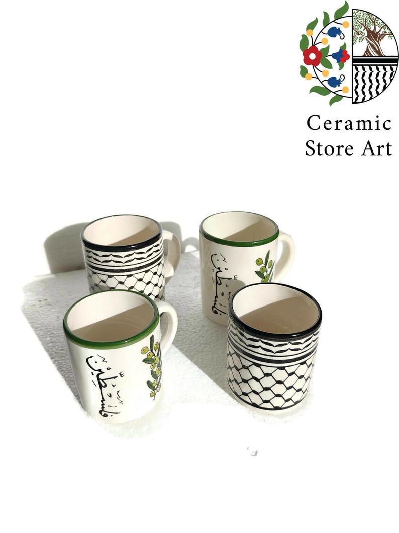 May include: Set of four white ceramic mugs with black and green designs. The mugs feature a geometric pattern, olive branches, and Arabic calligraphy.