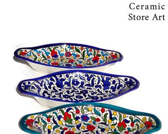 May include: Three ceramic serving dishes with a white background and colorful floral patterns. The dishes are oval shaped with a slight curve and have a blue, green, or white rim.