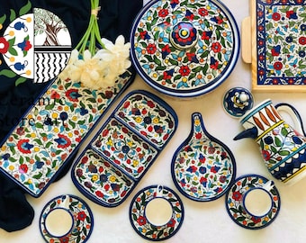 May include: A set of colorful ceramic dishes with floral patterns in shades of blue, red, yellow, and green. The set includes a large serving dish with a lid, a smaller serving dish, a pitcher, a set of two teacups and saucers, and a small dish with three compartments.