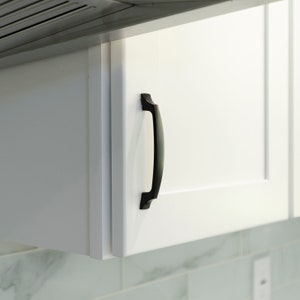 May include: White kitchen cabinet with a black metal handle. The cabinet is closed.