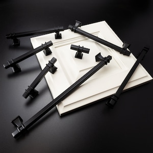 May include: A set of six black cabinet hardware pulls in various styles and sizes. The pulls are displayed on a white surface.