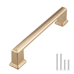May include: A gold cabinet pull with a rectangular shape and a slightly raised edge. The pull is 5 inches long and has a brushed finish.