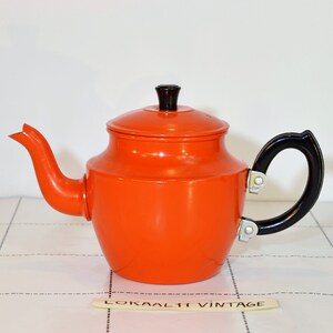 Pode incluir: Bule de esmalte laranja com alça e tampa pretas. A chaleira tem um estilo vintage.