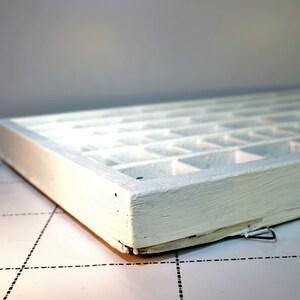 May include: White wooden box with multiple compartments. The box is empty and has a white painted finish.