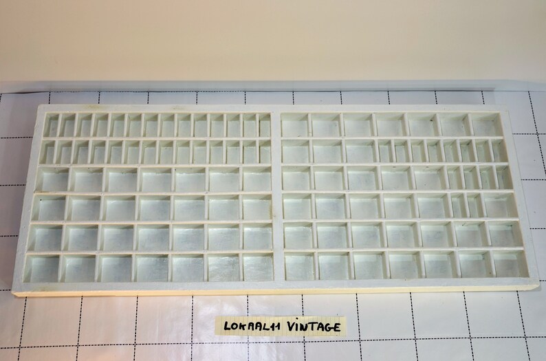 May include: White plastic storage box with multiple compartments. The box is empty and has a label that says "LOKAALI VINTAGE".