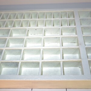 May include: White wooden storage box with multiple compartments. The box is empty and has a light wood finish.