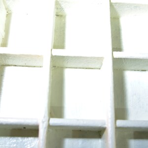 May include: White plastic storage box with multiple compartments. The box is empty and has a grid pattern.