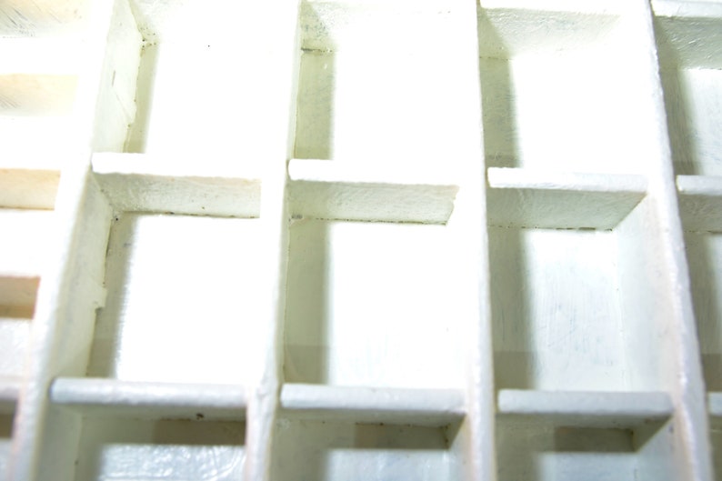 May include: White plastic storage box with multiple compartments. The box is empty and has a grid pattern.