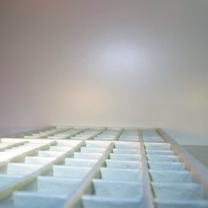 May include: A white plastic tray with multiple compartments, arranged in a grid pattern. The tray is empty and appears to be new.