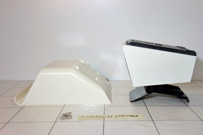 May include: Two white plastic bases for a vintage record player. The bases are different sizes and shapes. The larger base has a black top and a black stand.