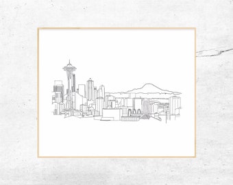 May include: A black and white line art drawing of the Seattle skyline featuring the Space Needle and Mount Rainier in the background. The illustration is presented within a thin, light-colored wooden frame against a textured white background.