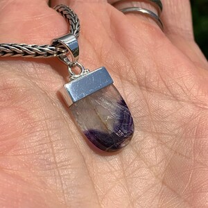 May include: A silver pendant with a purple and white fluorite stone. The pendant is on a silver chain.