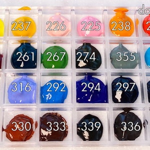 K&ouml;nnte beinhalten: Eine Plastik-Farbpalette mit 18 Farbt&ouml;pfen, die jeweils eine andere Farbe enthalten. Die T&ouml;pfe sind mit Zahlen von 211 bis 356 beschriftet. Die Palette ist mit "dot-sample" beschriftet.