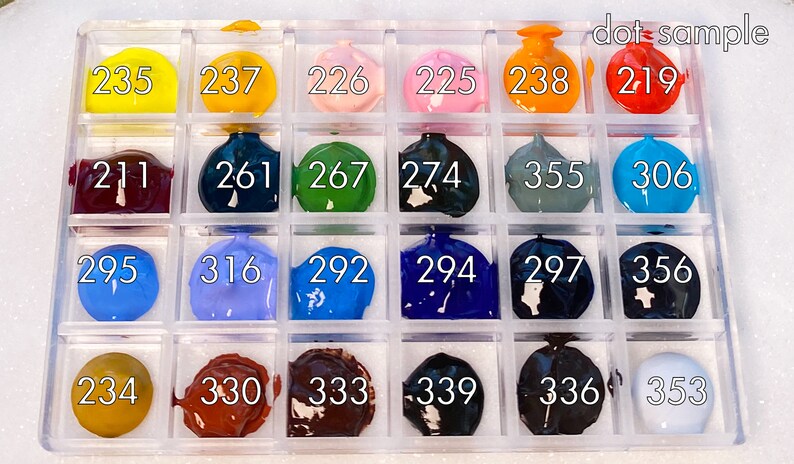 K&ouml;nnte beinhalten: Eine Plastik-Farbpalette mit 18 Farbt&ouml;pfen, die jeweils eine andere Farbe enthalten. Die T&ouml;pfe sind mit Zahlen von 211 bis 356 beschriftet. Die Palette ist mit "dot-sample" beschriftet.