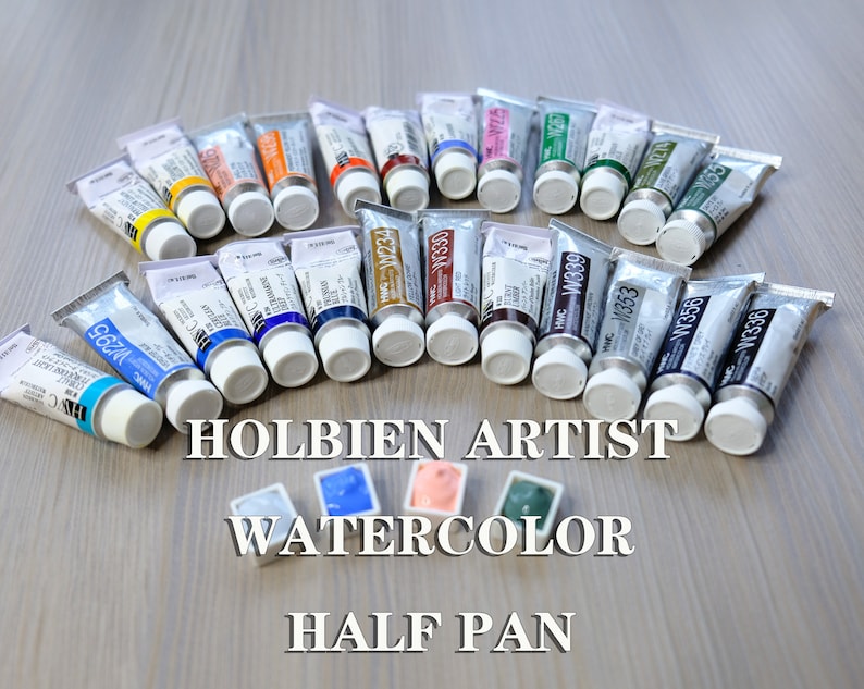 K&ouml;nnte beinhalten: Ein Satz Holbien Artist Aquarellfarben in Halb-Schalen. Die Tuben sind in einem Halbkreis auf einer Holzoberfl&auml;che angeordnet. Die Tuben sind mit der Farbnummer und dem Namen beschriftet. Die Farben umfassen W295, W234, W330, W339, W353, W356, W274, W338 und W055.