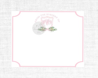 May include: A pink and white nursery note card with a pink border and a monogrammed crest with floral accents. The text reads "From the Nursery of".