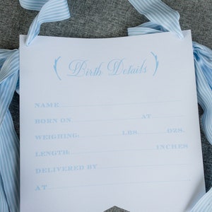 Może przedstawiać: Jasnoniebieski baner z tekstem "Birth Details" napisanym kursywą. Baner zawiera puste linie do wpisania informacji, takich jak imię, data urodzenia, waga w funtach i uncjach, długość w calach oraz kto odbierał por&oacute;d.
