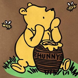 May include: A yellow cartoon bear with a honey pot that says "HUNNY" on a brown background. Two bees are flying around the bear. The bear is sitting on green grass. Blue circles are on the left side of the image.