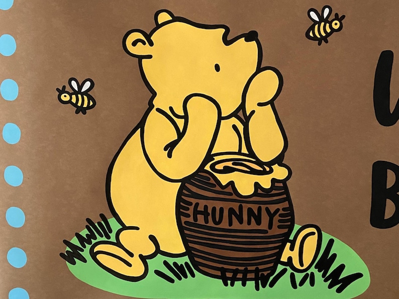 May include: A yellow cartoon bear with a honey pot that says "HUNNY" on a brown background. Two bees are flying around the bear. The bear is sitting on green grass. Blue circles are on the left side of the image.