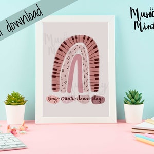 Puede incluir: Una descarga digital imprimible de un arcoíris rosa y marrón con notas musicales y un teclado de piano. El texto "sing - create - dance - play" está debajo del arcoíris. El texto "Musically Minted" está en la esquina superior derecha de la imagen.