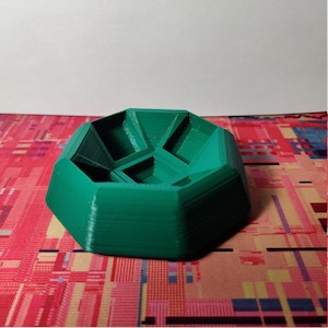 May include: A green, 3D printed, octagonal dish with a geometric design. The dish has a raised rim and a central depression.
