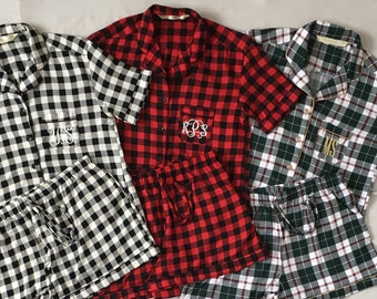 May include: Three sets of pajamas with short sleeves and matching shorts. The pajamas are made of a plaid fabric in black and white, red and black, and green and white.