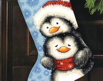 May include: A blue Christmas stocking with a penguin wearing a Santa hat and a smaller penguin wearing a red scarf. The stocking has the name "ELIZABETH" embroidered on the top.