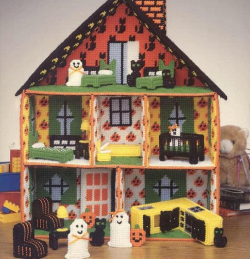 May include: A Halloween-themed dollhouse with a green roof and orange and black walls. The dollhouse is decorated with pumpkins, ghosts, and cats. It has a kitchen, bedroom, and living room.