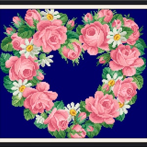 May include: A heart-shaped wreath made of pink roses and white daisies on a dark blue background.
