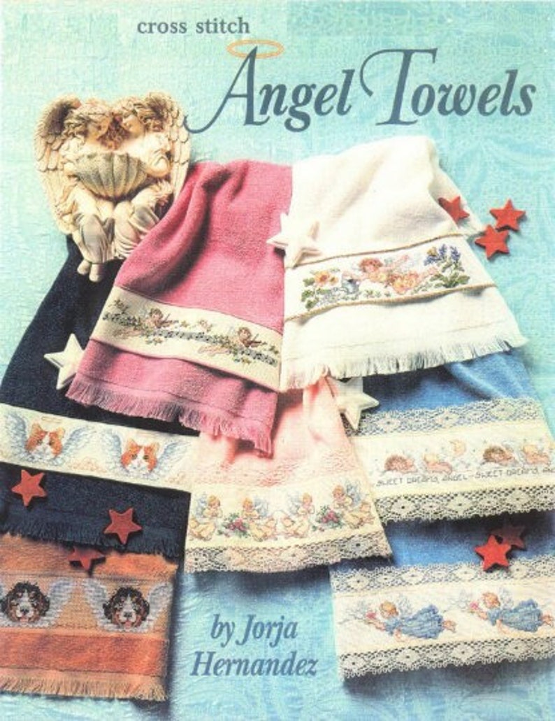 Op de afbeelding: Kruissteekpatronen voor engelhanddoeken. De patronen bevatten engelen, sterren en bloemen. De omslag van het boek bevat de titel "Angel Towels" en de auteur "by Jorja Hernandez".