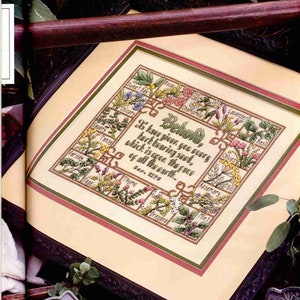 May include: A framed cross-stitch embroidery featuring a garden scene with various herbs and flowers. The text "Behold, I have given you every herb bearing seed, which is upon the face of all the earth." is included in the design.